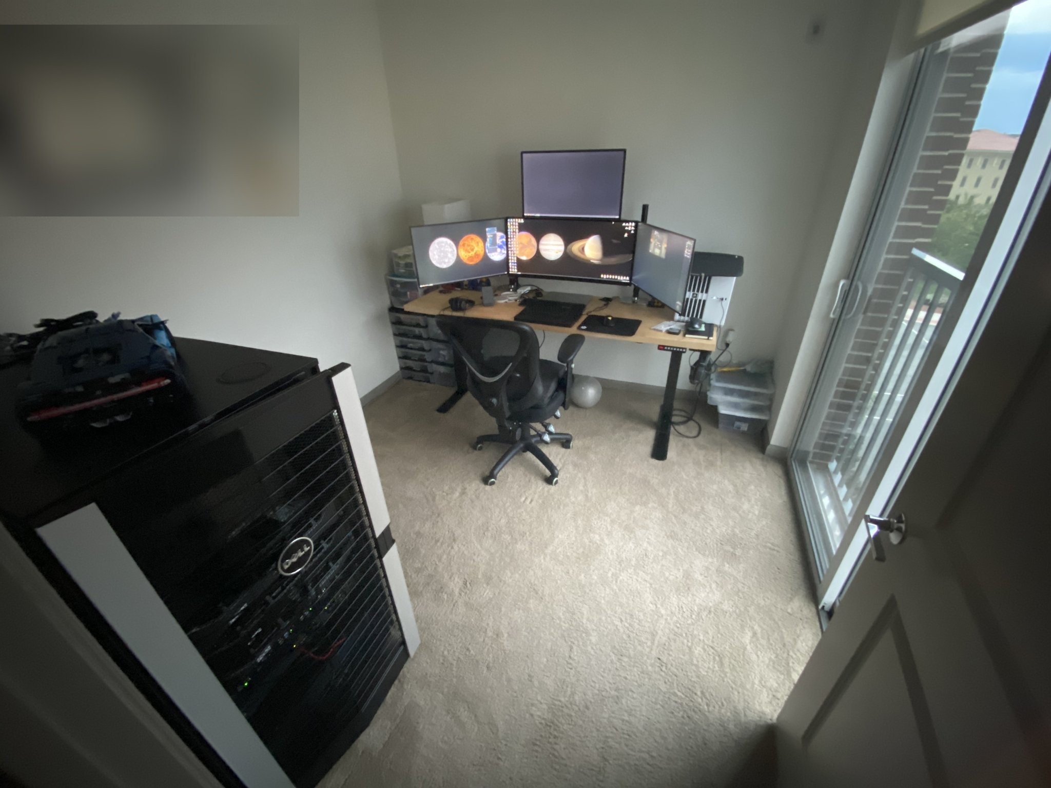 The office with the desk beside the window and the rack nearby.