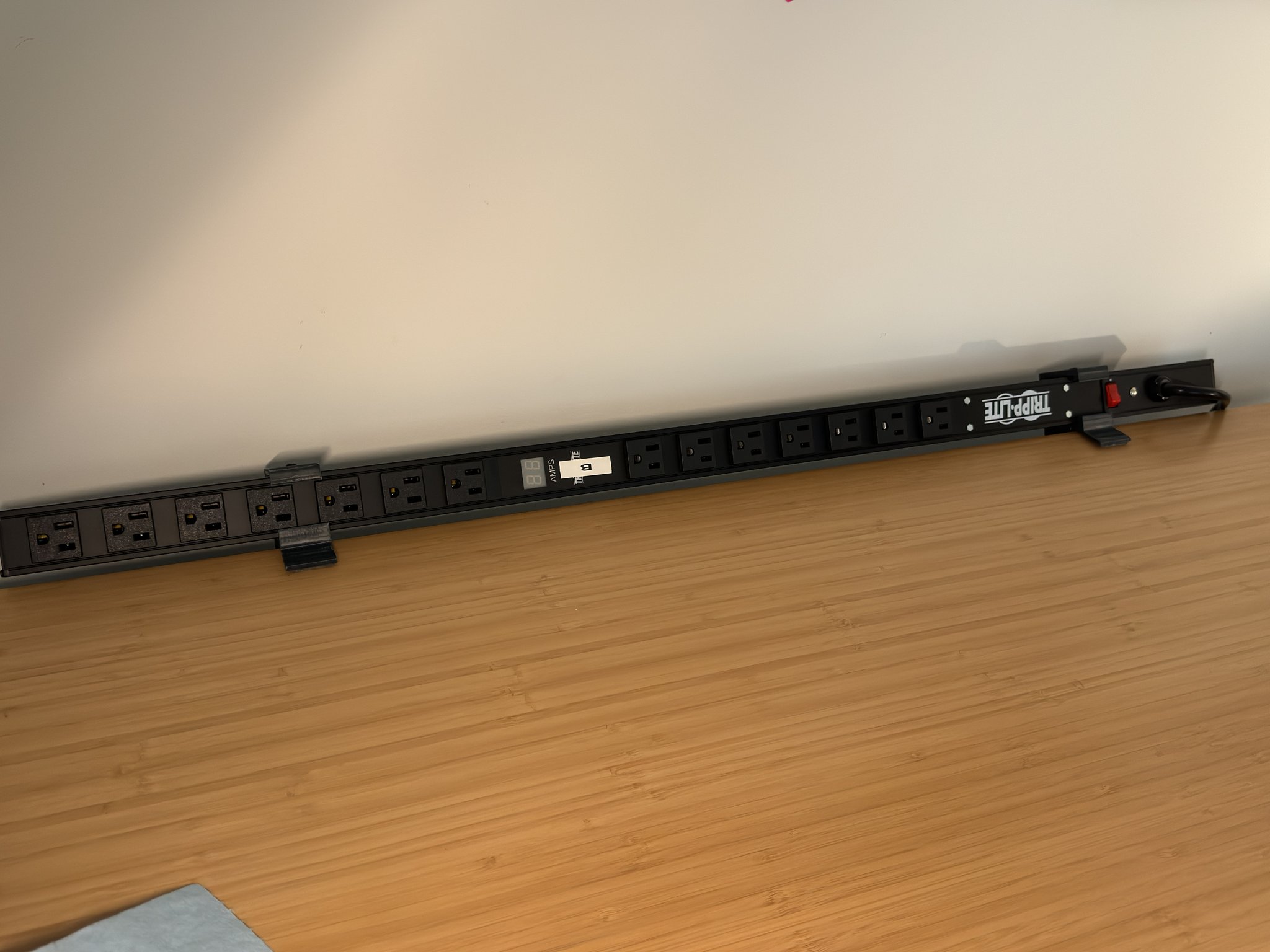 The power strip along the back edge of the desk.